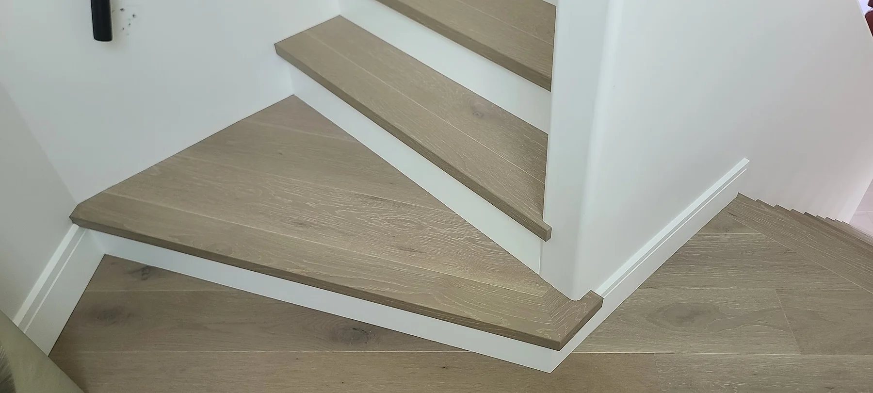 Precisely fitted hardwood wrapping around angled stair treads and a landing
