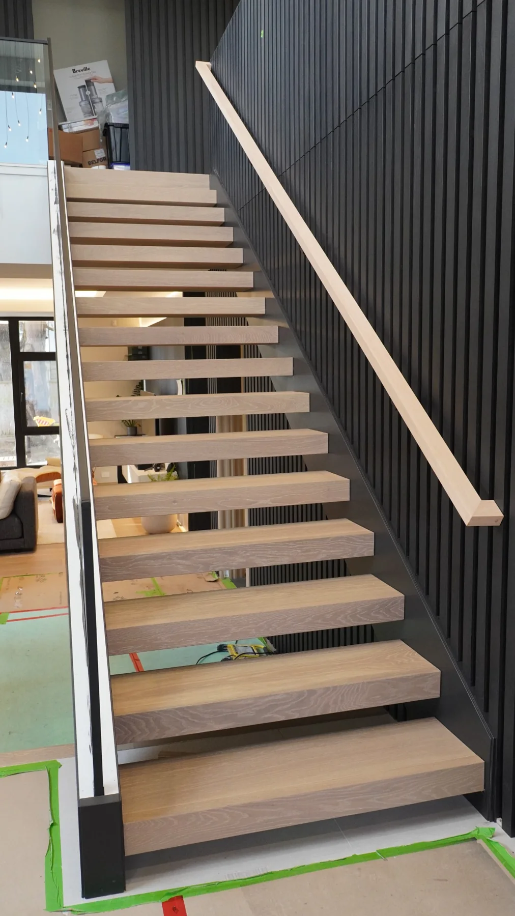 Floating oak stair treads beside black railings in the Richmond home